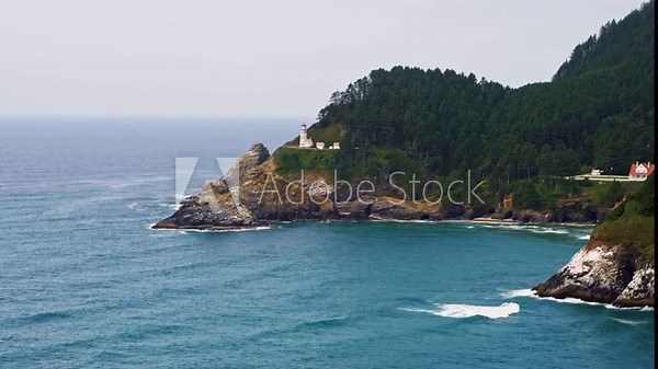 Pan left of Heceta Head Lighthouse on the Pacific Coast amidst rugged mountains, overlooking the expansive Pacific Ocean near Florence, Oregon. 4K UHD video.