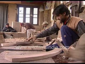 The men are working on the Kashmir craft, which involves intricately carving walnut wood.