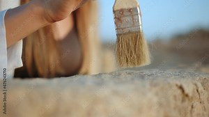 Archeological Excavation. Hand of Archaeologist With Tools (Brush) Sweep. Archaeological Digging Site: Great Female Archeologist Work on Excavation Site, Cleaning Cultural Artifacts with Brush.