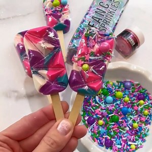 Things are getting heated with these Geo Cakesicles by @tallgirlbakes. 😍 Stephanie takes us on a trip with Purple, Pink and White Easy Candy and adds "Day Tripper" and Prism Powder for sparkle. ✨ Who wants one?! 💕 | Fancy Sprinkles