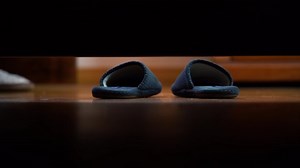 4k, Slippers on the floor.Man's foot put on slippers on the floor and go out. Camera under the bed. View from under the bed.