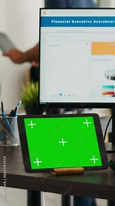 Vertical video Specialist having greenscreen on tablet and typing e commerce information on computer at office desk, working on increasing small company budget. Startup manager looks at isolated