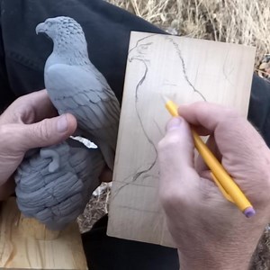 For my next walking stick, I'm going to carve a golden eagle on a crag holding a rattlesnake in its talons. Here, you can see I'm using the maquette I sculpted from polymer clay as reference while I draw my design onto a piece of tupelo wood. I'll be putting out a video on my Youtube channel on how I carve this walking stick topper as soon as the project is finished. | Stinnett Sticks
