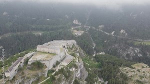 Aerial drone shot orbiting around the Victor-Emmanuel Fortress revealing the limestone mountain cliff and epic landscape on which the historical ancient fort was built in Aussois, France