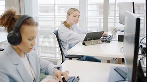 In a modern workplace, employees are adept at multitasking, using technology like tablets and headsets while typing, highlighting productivity and innovation in corporate communication