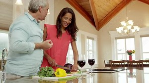 A man and woman stand in the kitchen preparing food on the counter