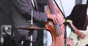 Concert view of a contrabass violoncello player with vocalist and musical rock band during jazz orchestra band performing music, violoncellist cello jazz player on stage