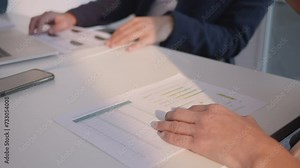 Company employee holding paper with statistics data in hands and collaborating with team close up. Report analysis and teamwork in office meeting concept