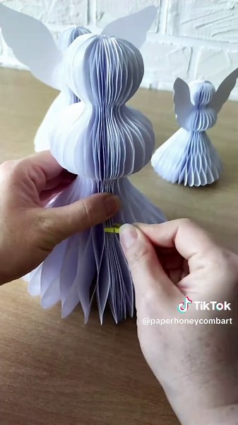 Papierowe aniołki w świątecznej scenerii — lekkie, delikatne i pełne zimowego klimatu. Ich harmonijkowa forma sprawia, że wyglądają jak małe dekoracyjne rzeźby, które od razu wprowadzają magię do wnętrza. W otoczeniu czerwonych i białych choinek tworzą idealny, przytulny kadr gotowy na świąteczne inspiracje DIY. These paper angels bring a soft winter charm — light, airy and beautifully shaped like delicate holiday sculptures. Surrounded by red and white trees, they instantly create a cozy, festi