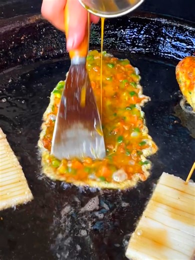 Hidden in the busy streets of Liuyang, Hunan, egg wrap cakes are made fresh to order. Beaten eggs spread thin on a hot pan, quickly wrapped around a fluffy cake and rich fillings, then finished with a glossy sauce. The aroma fills the air as golden layers meet soft texture inside. One bite captures the charm of Liuyang’s street food—humble, hearty, and irresistibly satisfying. #Hunan #Foodie #FoodLover | Rednet.cn红网