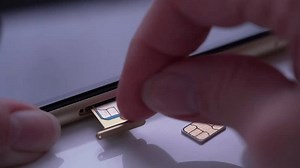 clip-1100784525-person-inserting-sim-card-into-back-mobile