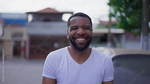 One joyful black man laughing and smiling while standing outside in city street, happy African American person with friendly charismatic expression