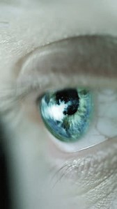 Close-up footage of an eye reflecting diverse scenes, capturing a range of visual details and settings in the eye's reflection
