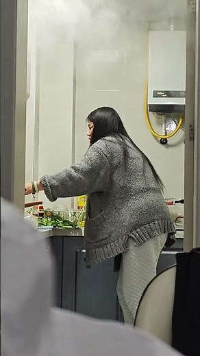 Woman cooks while heavy steam fills kitchen in Zhejiang, China