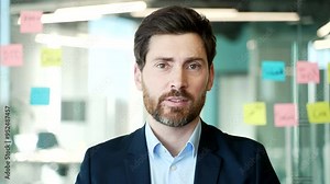 Webcam view. Businessman talking on a video call looking at camera sitting in office. A man in a formal suit has a business meeting, speaks remotely, communicates at an online conference. Close up