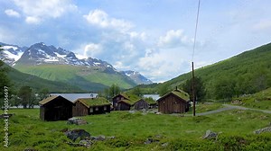 Aerial footage captures remote mountain villages with green roofed houses, fields, lakes, and picturesque rural landscapes, showcasing serene rural life, Innerdalen valley Norway