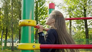 Healthy woman using the pull up bar to train all muscle groups. Sportswoman training outdoors. Fitness female during her morning workout session. Close-up in 4K, UHD