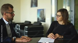 Good looking young businessman closing a deal with a female client while she signs a contract