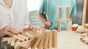 Slow motion of boy pushing wooden block and starting domino effect. Wooden blocks falling in chain. Concept of children education at home during lockdown and staying at home Stock Video