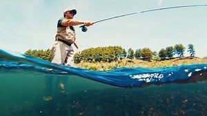 Fly fishing splitted underwater view. Angler casts the fly on the rapid river