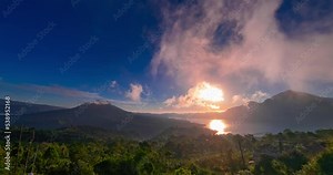 Hyperlapse of sunset with view on Batur and Abang volcanoes and lake on Bali. Clouds are moving fast in blue sky, the sun is setting