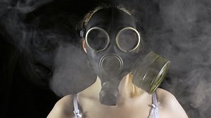 Young woman in gas mask and smoke