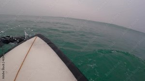 Surfer in wetsuit riding on surfboard on breaking wave. First-person view of surfing in ocean