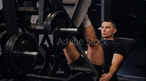 leg muscles, Fit male athlete, Handsome trainer. Sportsman uses leg exercise machine to develop muscle mass.