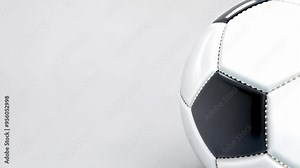 A close-up of a classic black and white soccer ball highlights its hexagonal and pentagonal panels against a neutral gray background, perfect for sports-related projects or marketing.