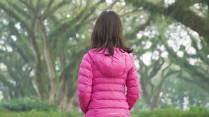 Back view of little girl enjoying holiday while walking under green trees with big branches at De Djawatan forest in Banyuwangi, East Java, Indonesia. Shot in 4k resolution