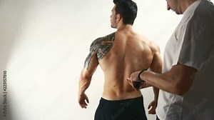 Bodybuilding competition contestant being oiled by assistant or model getting ready before photoshoot