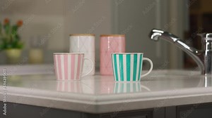 Tea table setting. Two mugs and utensils for tea and sugar stand on a white table in the kitchen. Smooth movement of the camera down