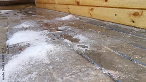 Water drips from the roof onto the snow and onto the sidewalk. Spring thaw, drop close-up. The concept of awakening nature, warm days, the end of winter. Dacha plot, back yard with wooden gazebo