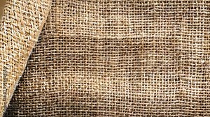 Close-up of natural jute burlap fabric, featuring a coarse texture and earthy tones. Its rustic weave makes it ideal for eco-friendly themes, crafts, and interior design.