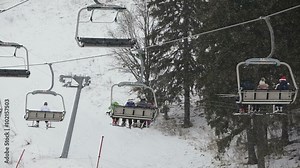 Ski lift chairs on winter day.Modern chair ski lift in ski resort.people ride the ski chair lift up the mountain.Ski chair lift with skiers