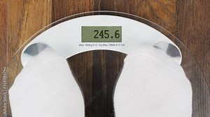 Overweight on bathroom scales. Digital display with an inscription OVERWEIGHT. Overweight and obese concepts. A person steps on the scales to check her weight. First-person view
