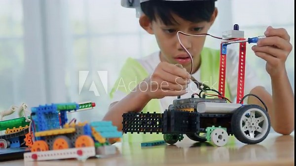 Asian boy engineer working on robotics project in a STEM education class. child is focused on assembling and learning about a small robot or electronic project. engineering, innovation, technology.