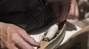 close-up of A skilled craftsman's hands who weaves a traditional wool fabric on old antique wooden loom in Ladakh, India