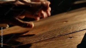 Close-up video of fingers drumming on a wooden surface with dramatic shadows and slow zoom out camera movement.