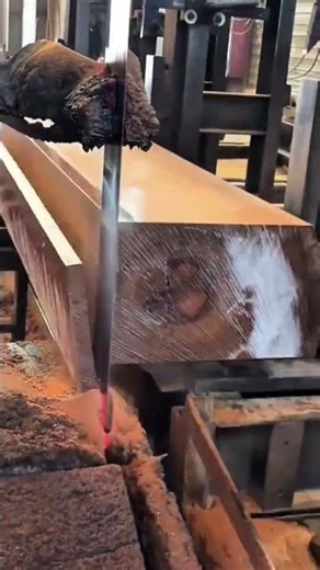 cutting the large wooden beam using an industrial saw