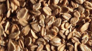 Oat Flakes Background Slowly Moving Downward - Top View, Low Key Light. Scattered Dry Oat Flakes. Healthy Breakfast and Diet Eating Ingredients