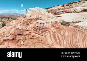 Aerial fly through of White Pocket in Vermilion Cliffs Arizona reveals swirling sandstone layers dramatic rock textures and desert scenery in bright midday light for natural beauty and adventure Stock Video Footage - Alamy