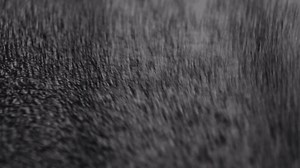 A sheet of black layered polystyrene foam material falling in slow motion on textured wood surface