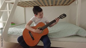 Boy learning to play acoustic guitar. Boy is practicing acoustic guitar in his room
