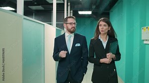 Business meeting, couple of top managers goes to a meeting, the interior of a office space, a walk through the office inside a skyscraper, front view.