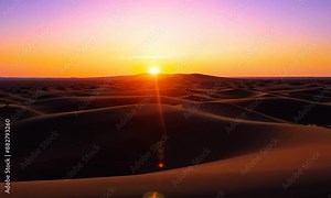 Stunning sunset over desert dunes creates a dramatic and serene landscape The vibrant colors of the sky blend beautifully with the shadows cast by the dunes, the natural beauty of desert