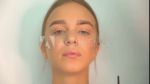 A professional eyebrow specialist models and colors the lines on the face of a beautiful European model. Young girl in Beauty saloon.