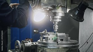 Operator using a milling machine to shape metal workpiece in industrial workshop, showcasing intricate details of metalworking process