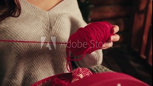 Girl in a gray sweater unravels a clew of red thread Stock Video