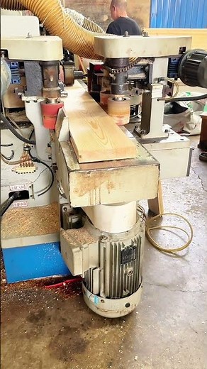Precision Woodworking: Man Feeds Timber into a Planing Machine